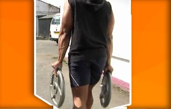 Man voert een farmer carry met twee stalen halterplaten uit