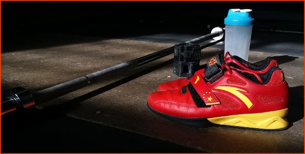 Paar rode squat schoenen en een barbell