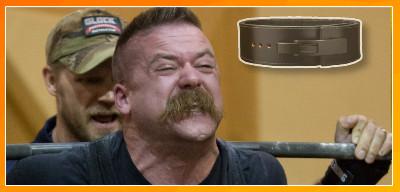 Een man met snor die moeilijk kijkt tijdens squatten