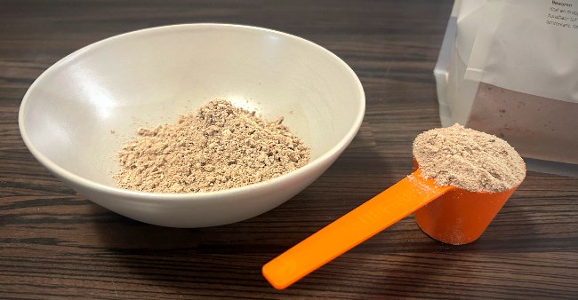 Een kom met Upfront oats en rechts daarnaast een met oats gevulde oranje Upfront scoop